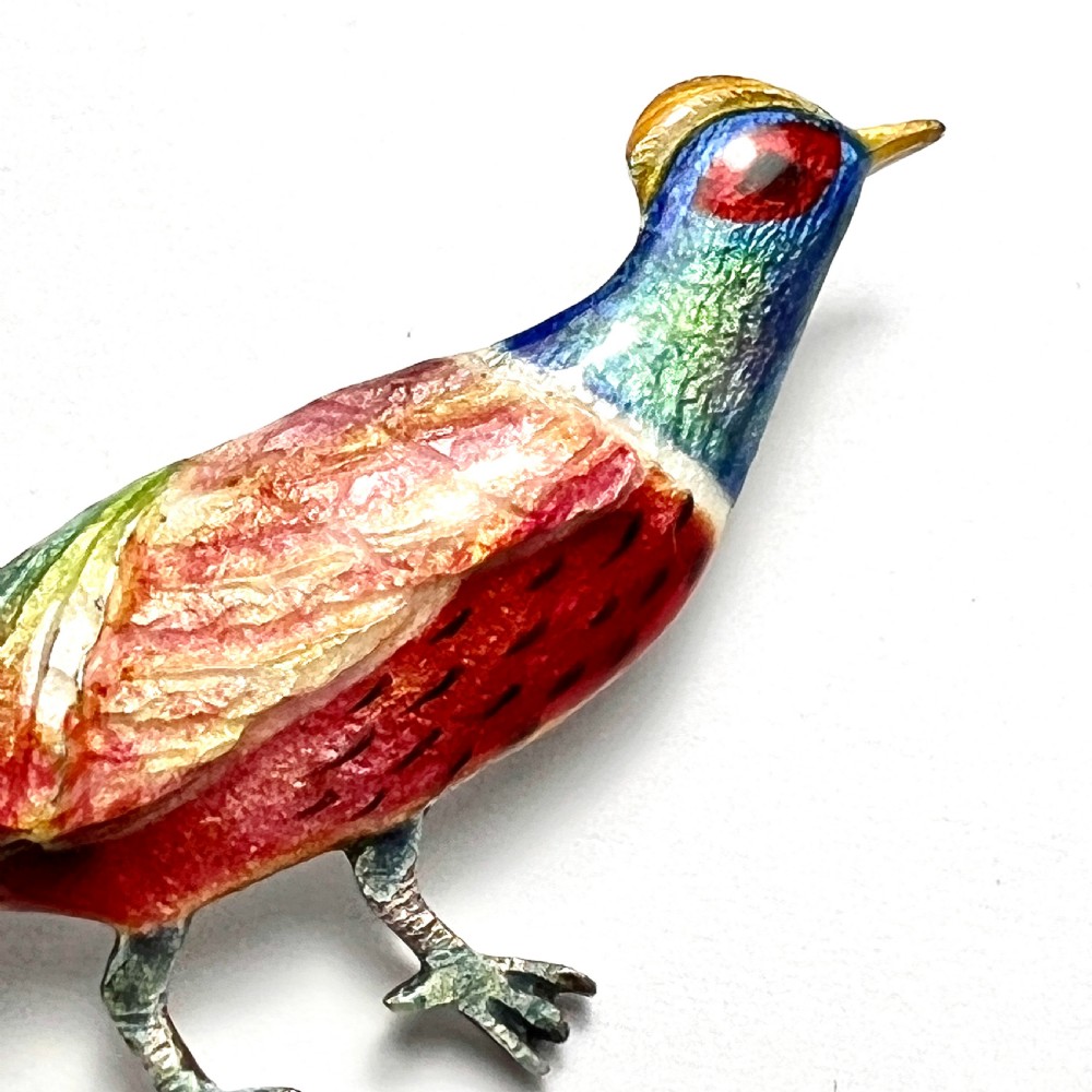 An Art Deco silver brooch shaped like a standing pheasant featuring red, green, blue, and gold enamel detailing. View VI