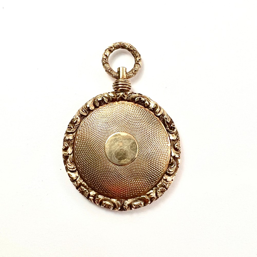 A Victorian 15ct yellow gold oval locket pendant featuring an engine-turned centre, a blank central cartouche, and a chased floral border. View II