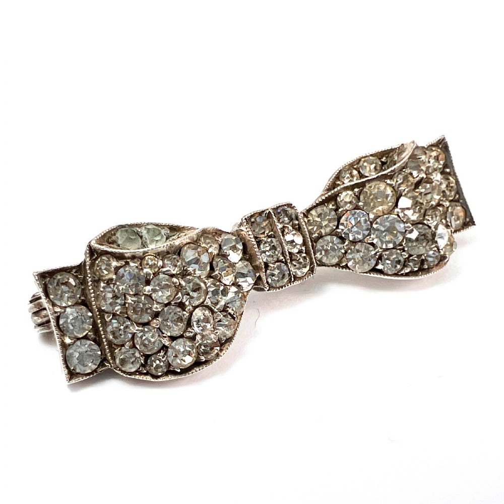 A vintage sterling silver bow brooch densely set with faceted clear paste stones.