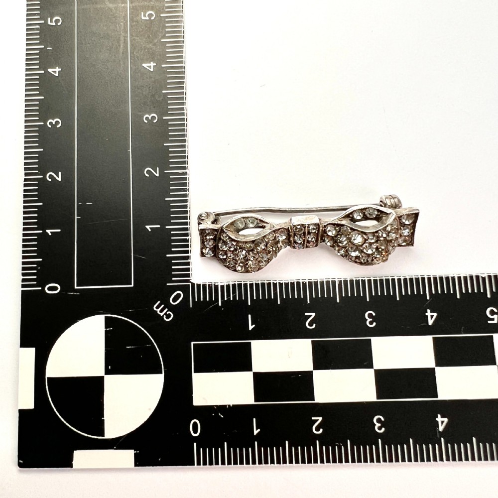 A vintage sterling silver bow brooch densely set with faceted clear paste stones. View VI