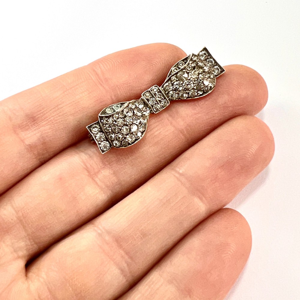A vintage sterling silver bow brooch densely set with faceted clear paste stones. View VII