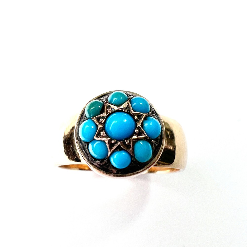 A Victorian 18ct yellow gold ring featuring a central round panel set with turquoise cabochons forming an eight-pointed star motif.