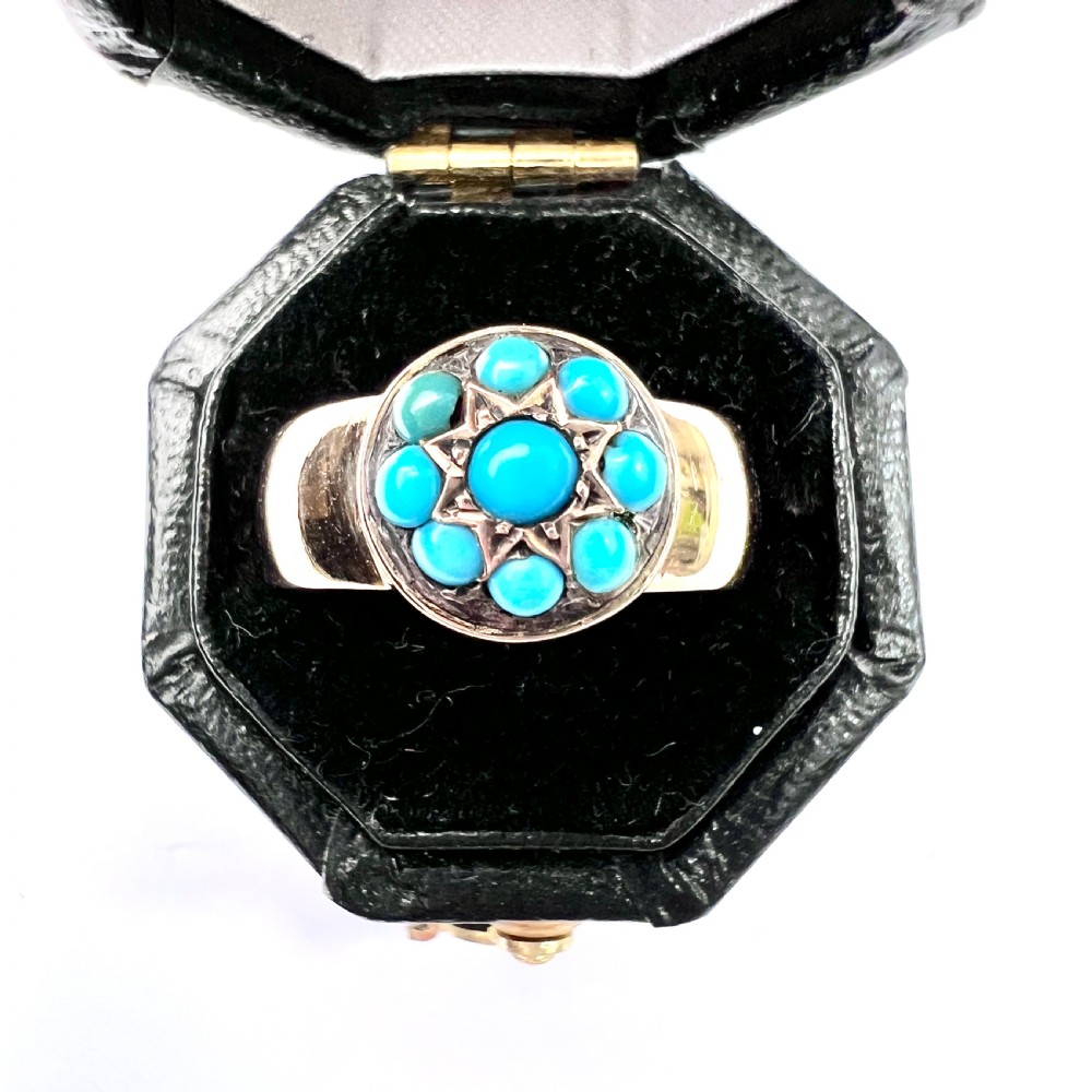 A Victorian 18ct yellow gold ring featuring a central round panel set with turquoise cabochons forming an eight-pointed star motif. View V