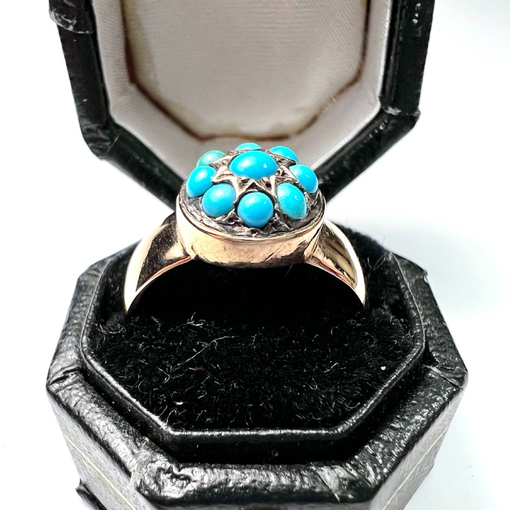 A Victorian 18ct yellow gold ring featuring a central round panel set with turquoise cabochons forming an eight-pointed star motif. View VI