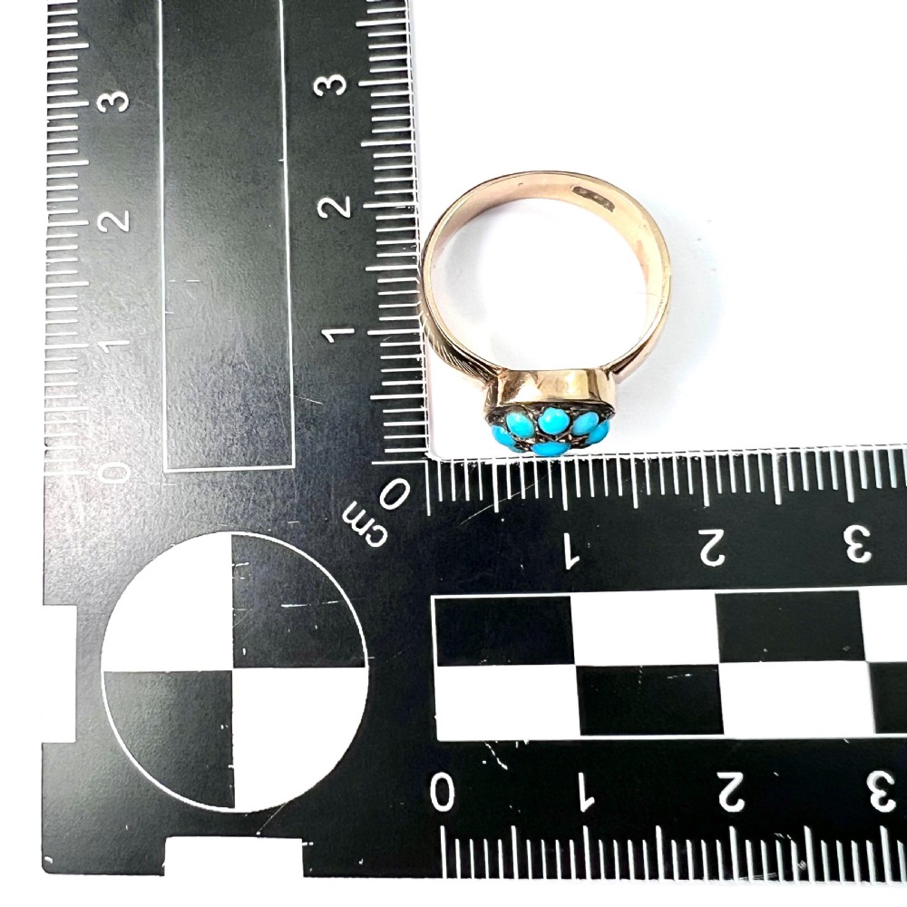 A Victorian 18ct yellow gold ring featuring a central round panel set with turquoise cabochons forming an eight-pointed star motif. View VII