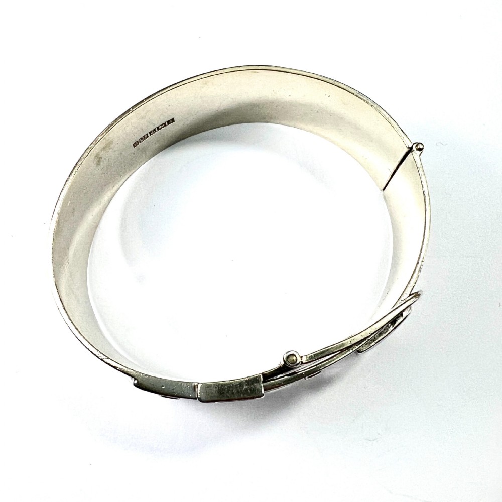 A wide hinged silver buckle bangle decorated with detailed foliate engraved patterns across the front. View VIII
