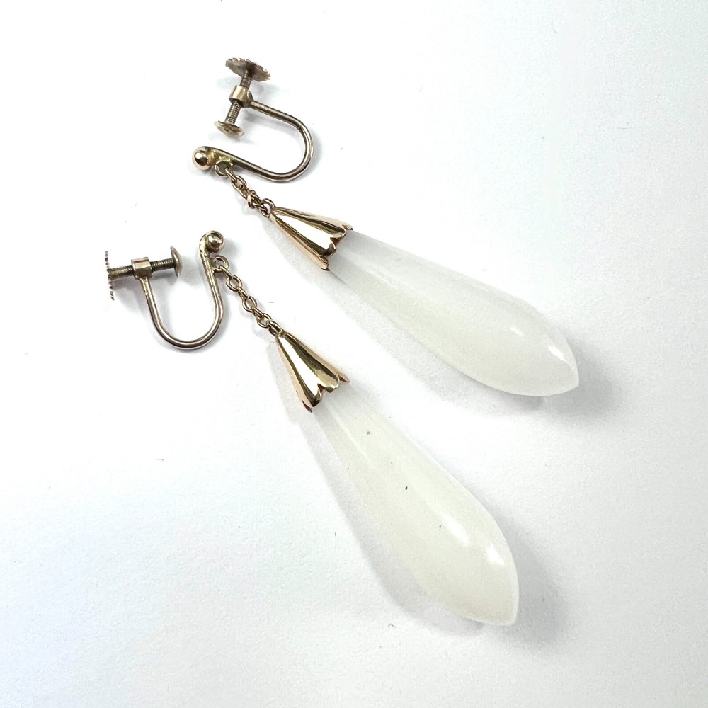 A pair of antique 9ct gold drop earrings featuring smooth, teardrop-shaped white chalcedony stones suspended on short chains from screw-back fastenings.