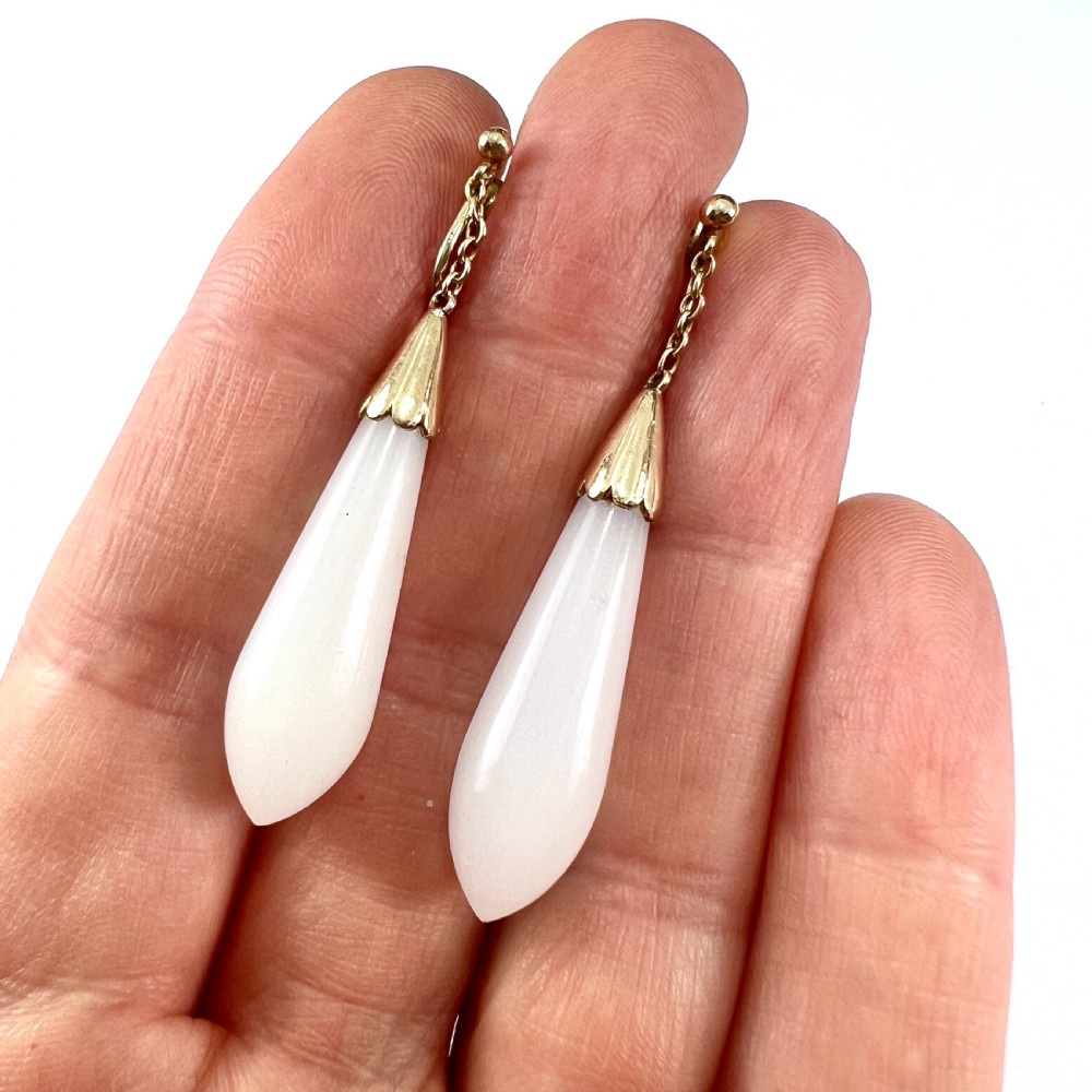 A pair of antique 9ct gold drop earrings featuring smooth, teardrop-shaped white chalcedony stones suspended on short chains from screw-back fastenings. View V