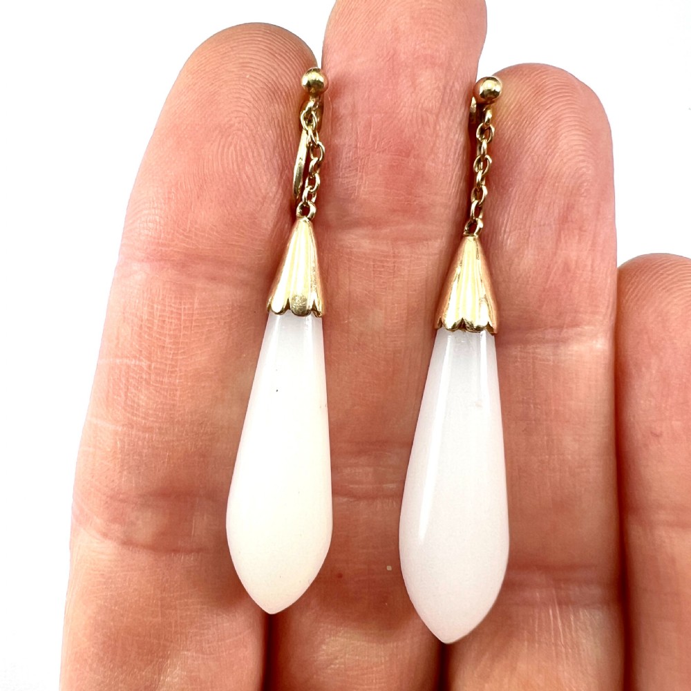 A pair of antique 9ct gold drop earrings featuring smooth, teardrop-shaped white chalcedony stones suspended on short chains from screw-back fastenings. View VI