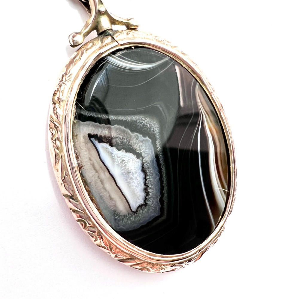 A Victorian 9ct gold oval agate locket with engraved border detailing suspended from a gold chain. View III