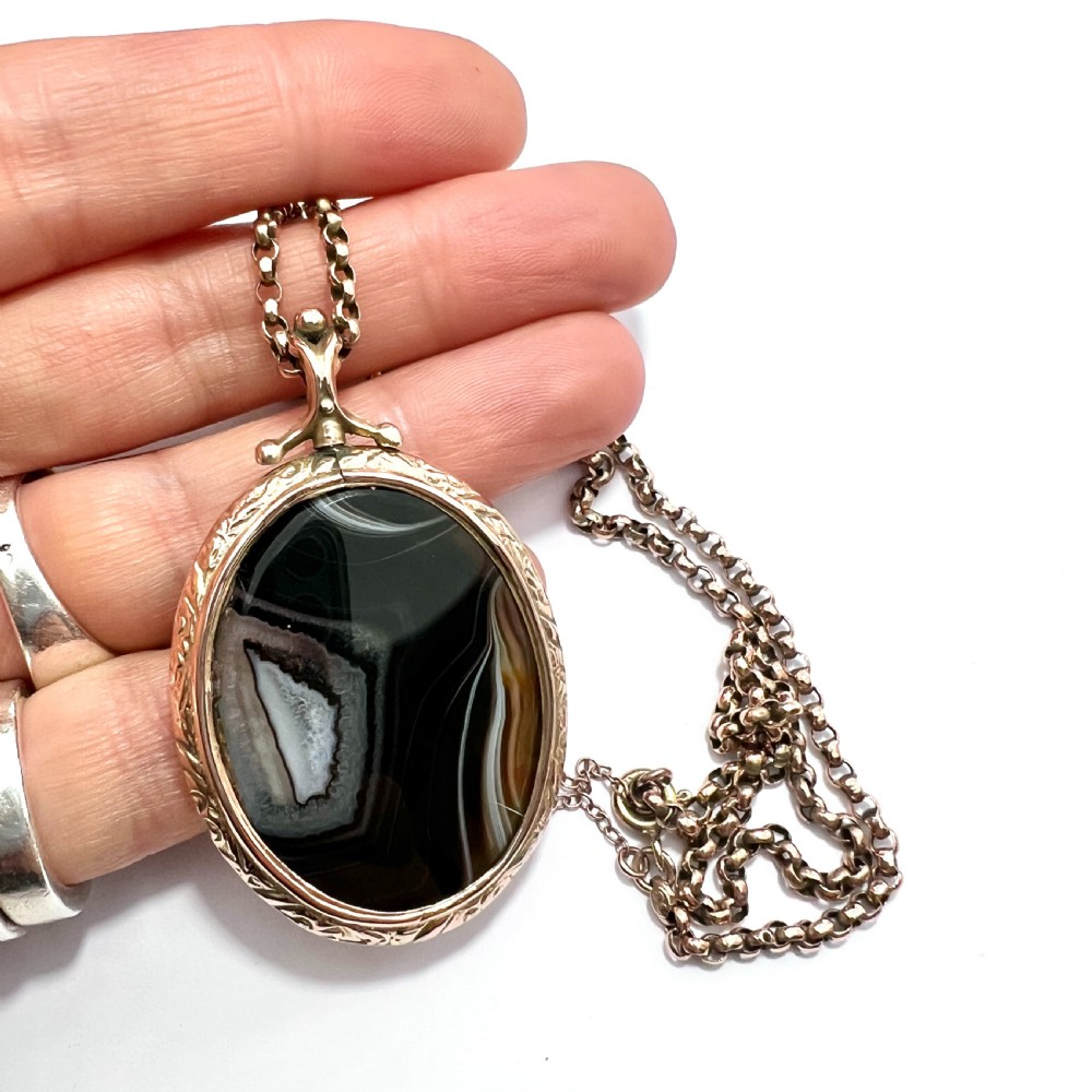 A Victorian 9ct gold oval agate locket with engraved border detailing suspended from a gold chain. View XI