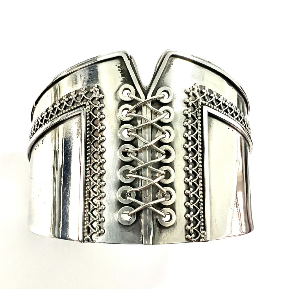 A wide sterling silver hinged cuff bangle featuring a corset-style laced centre detail flanked by intricate filigree borders. View II