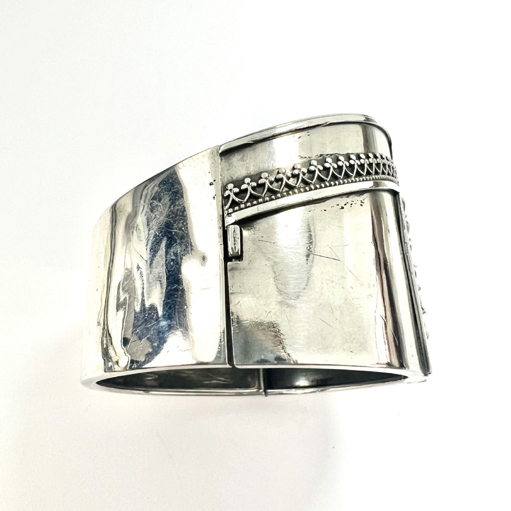 A wide sterling silver hinged cuff bangle featuring a corset-style laced centre detail flanked by intricate filigree borders. View V