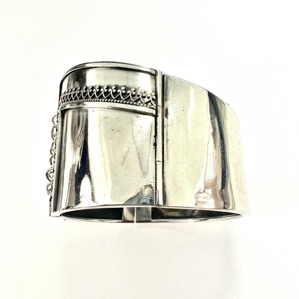 A wide sterling silver hinged cuff bangle featuring a corset-style laced centre detail flanked by intricate filigree borders. View VI