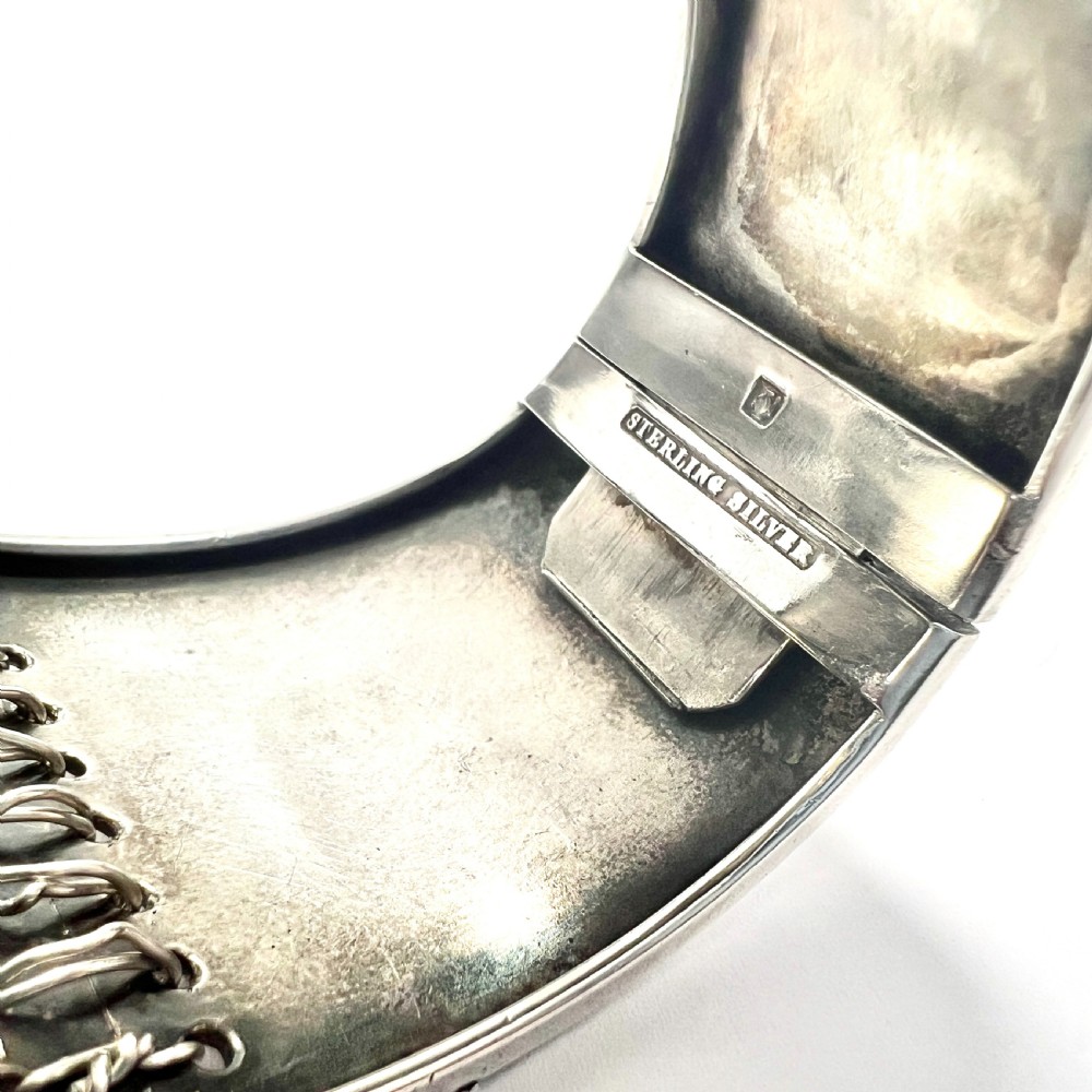 A wide sterling silver hinged cuff bangle featuring a corset-style laced centre detail flanked by intricate filigree borders. View VII