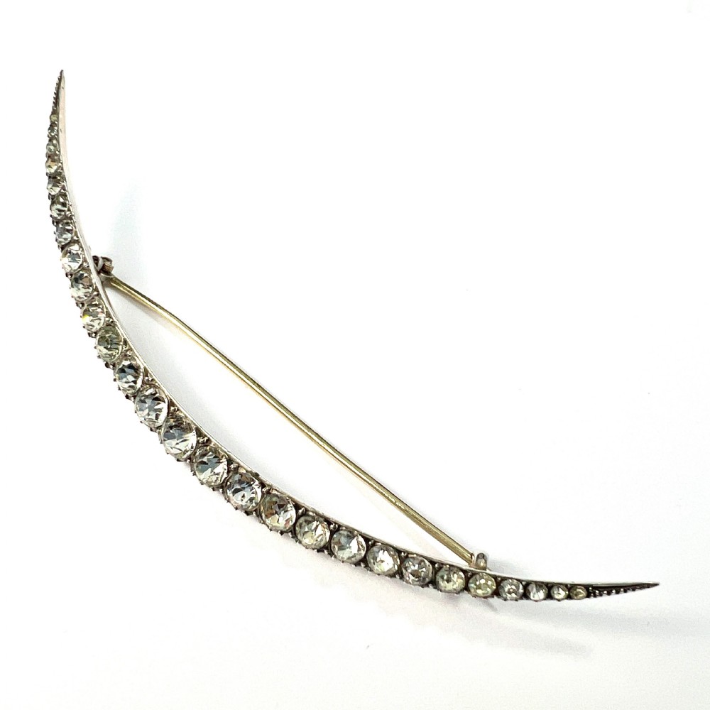 A Victorian crescent moon brooch set with a single row of graduated clear paste stones in a silver setting with a long pin fastening. View III