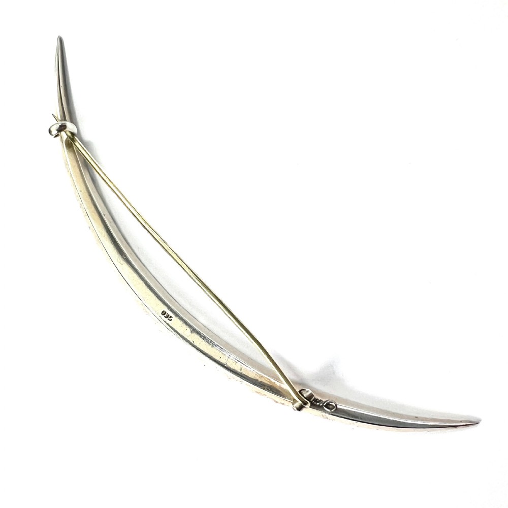 A Victorian crescent moon brooch set with a single row of graduated clear paste stones in a silver setting with a long pin fastening. View VII