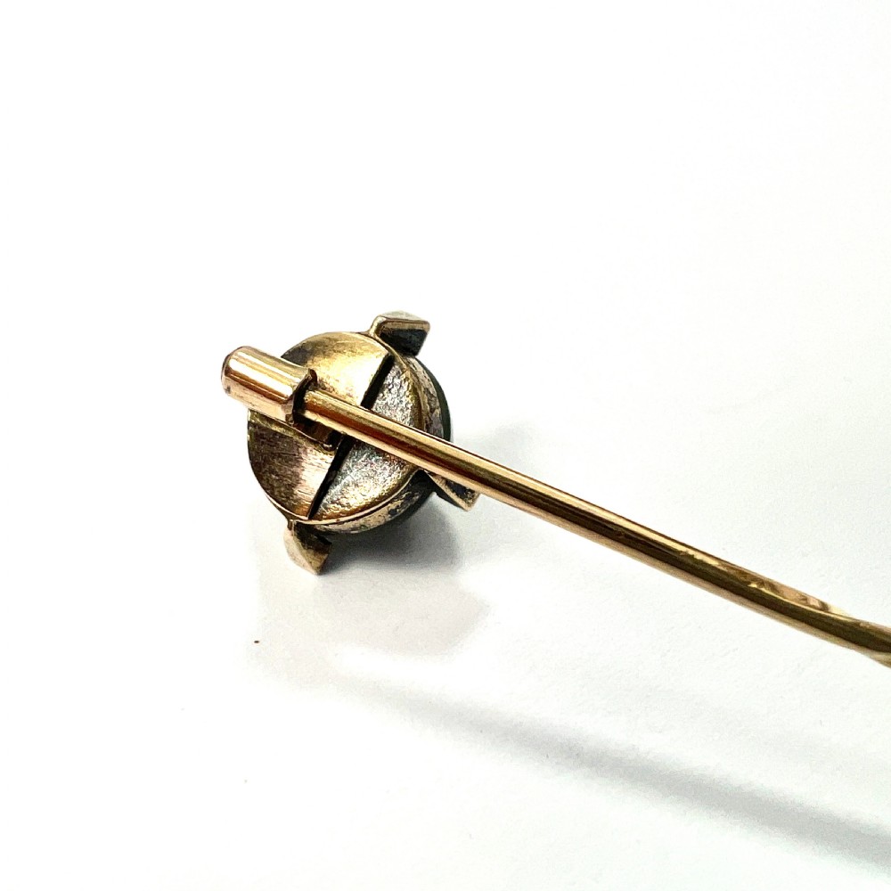 An antique 9ct gold stick pin featuring a central spherical green gemstone set with four small rose-cut diamonds, displayed inside an open velvet-lined leather jewellery box. View IV