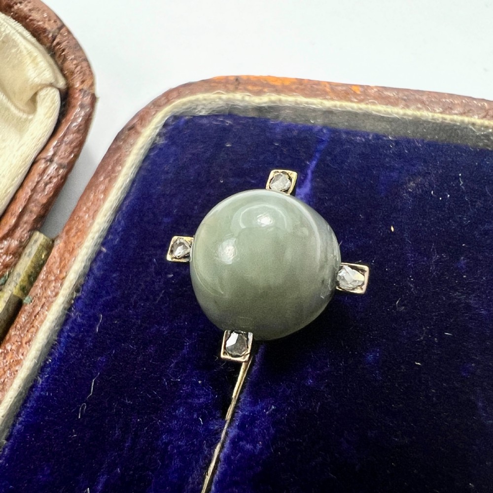 An antique 9ct gold stick pin featuring a central spherical green gemstone set with four small rose-cut diamonds, displayed inside an open velvet-lined leather jewellery box. View VIII