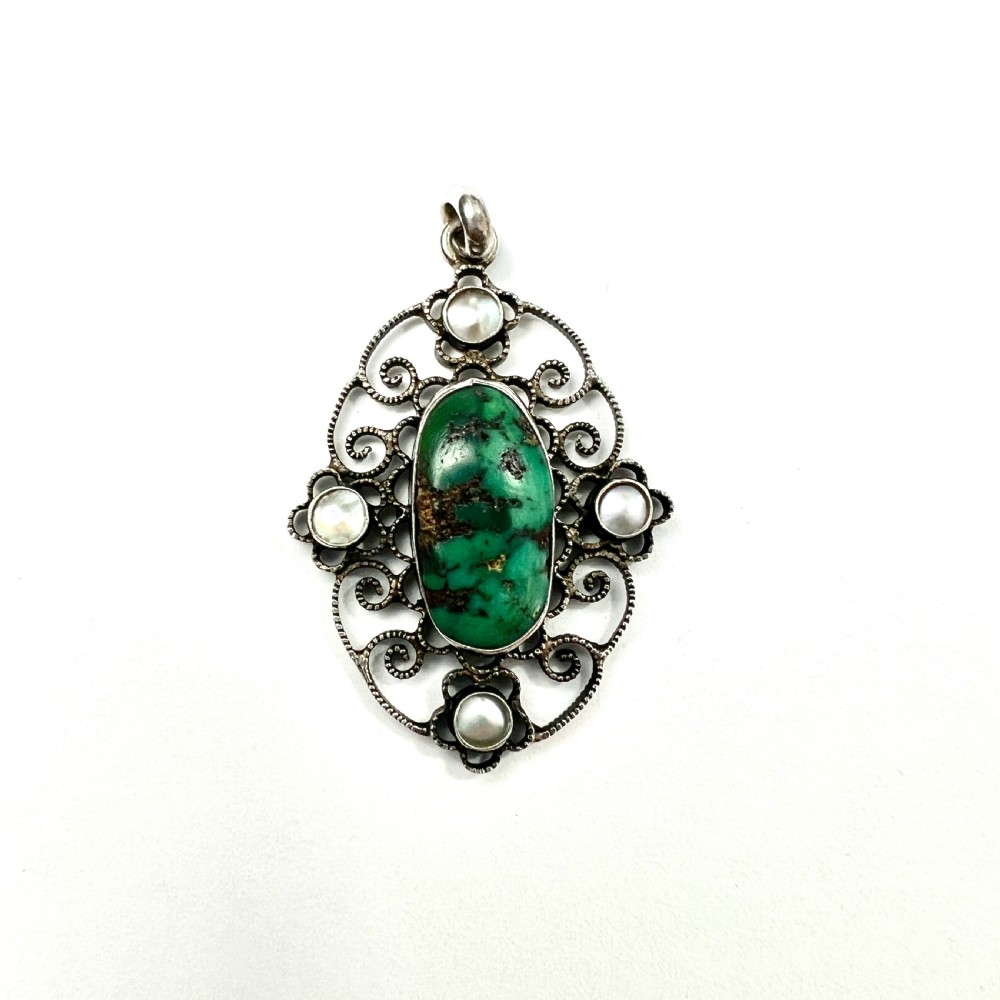 An oval silver pendant featuring an openwork scrollwork design set with a central green turquoise matrix cabochon and four small pearl accents. View II