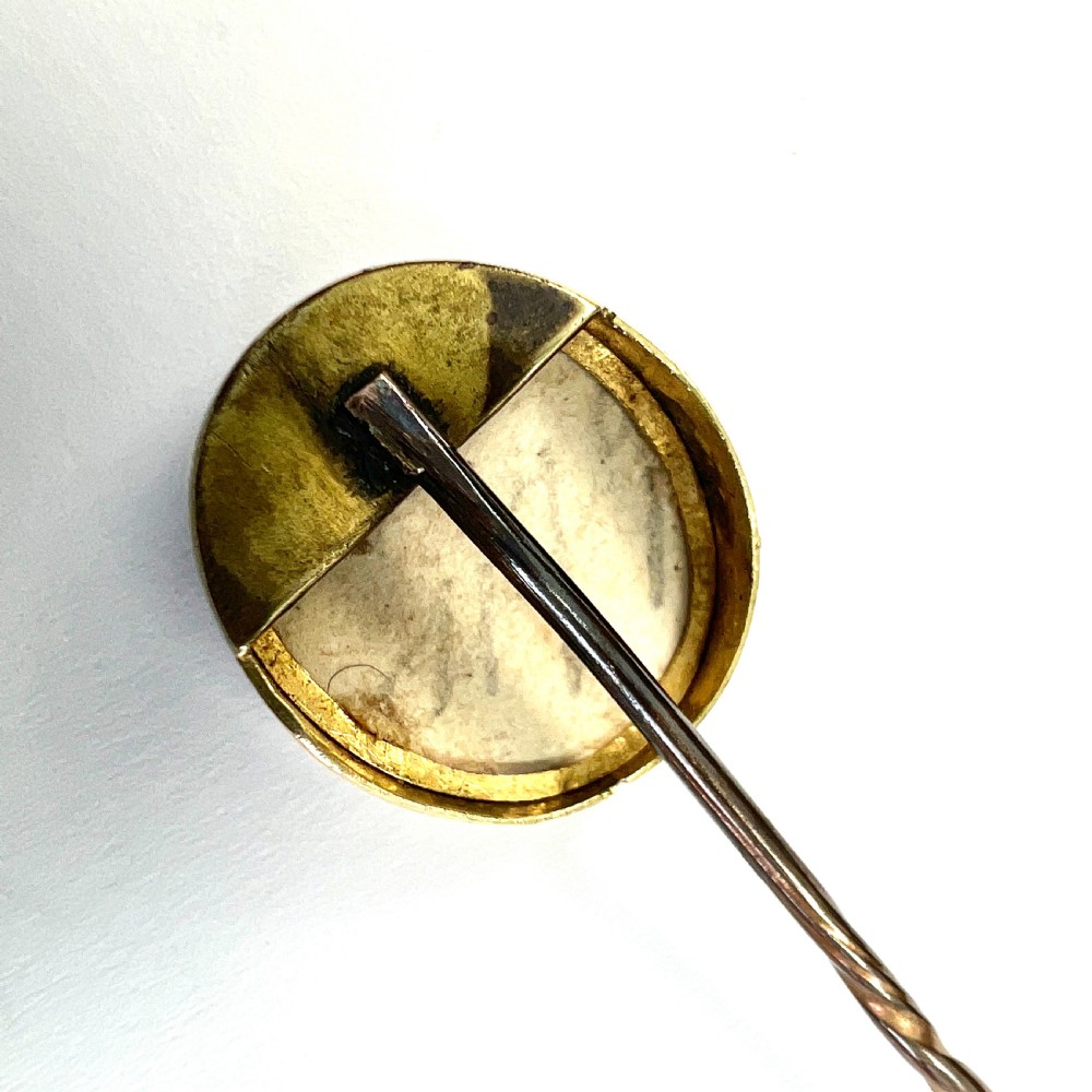 An antique gold stick pin featuring an oval miniature portrait painting of a lady in a blue dress with dark curls. View III