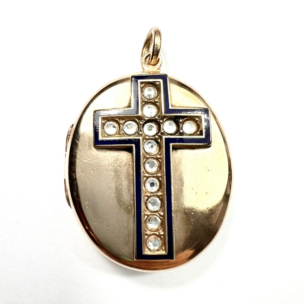An oval rolled gold Victorian locket featuring a central blue enamelled cross set with round paste stones.