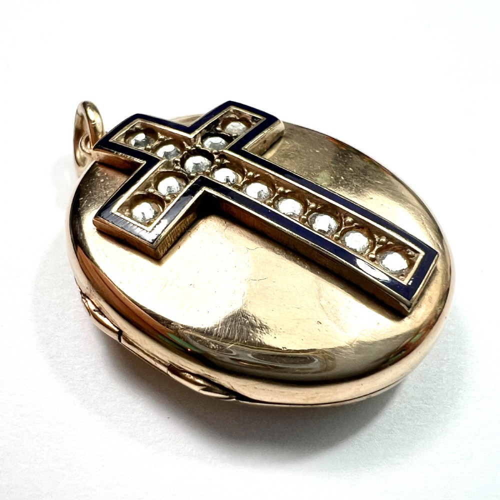 An oval rolled gold Victorian locket featuring a central blue enamelled cross set with round paste stones. View II