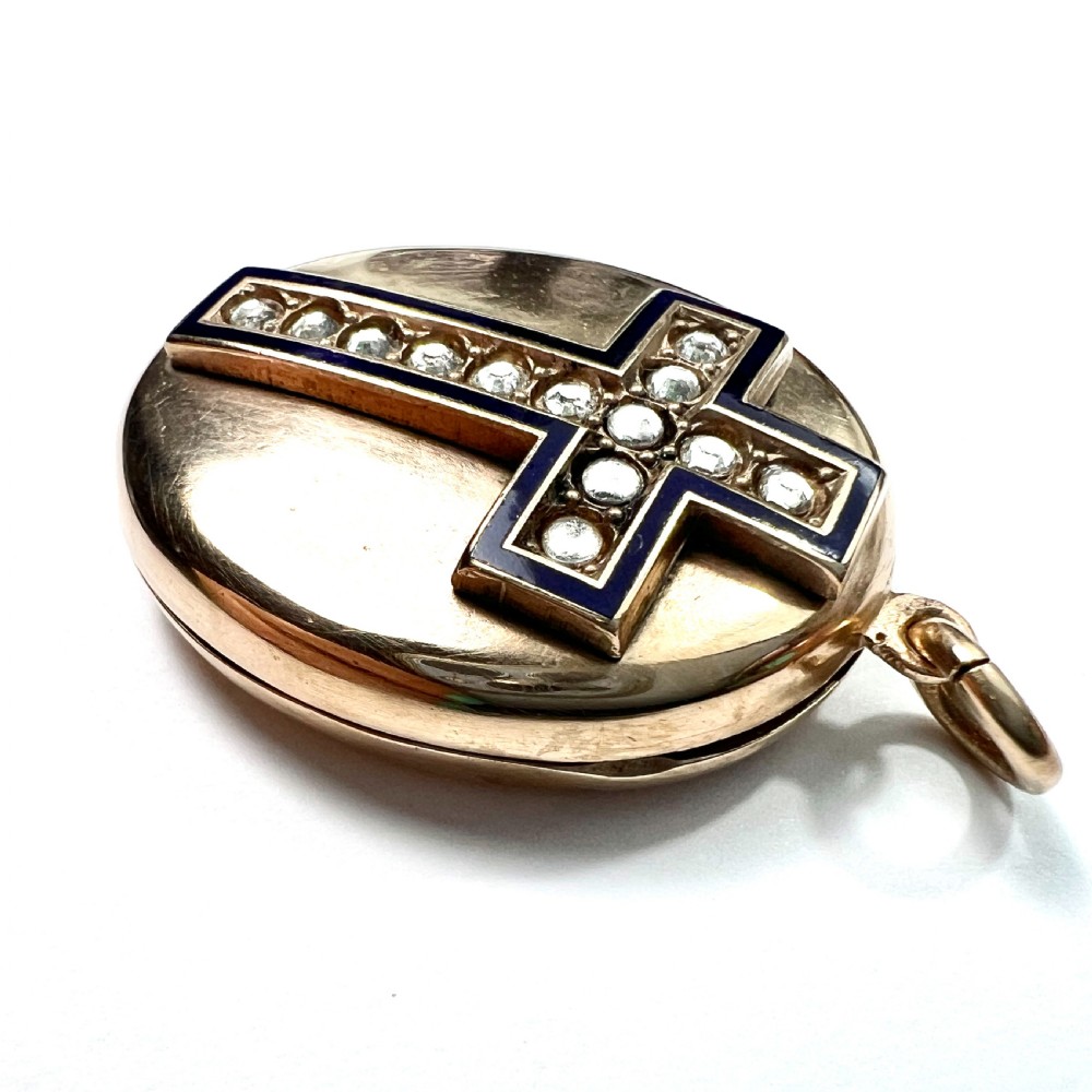 An oval rolled gold Victorian locket featuring a central blue enamelled cross set with round paste stones. View III
