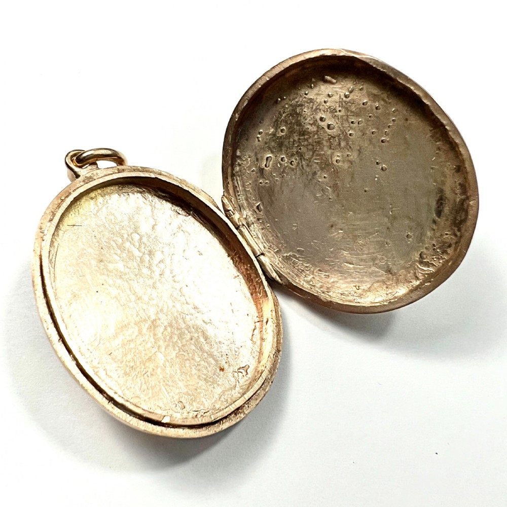 An oval rolled gold Victorian locket featuring a central blue enamelled cross set with round paste stones. View V