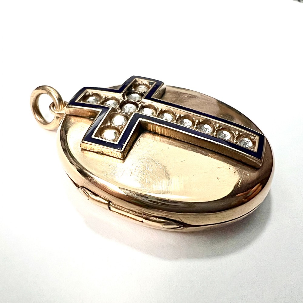 An oval rolled gold Victorian locket featuring a central blue enamelled cross set with round paste stones. View VI