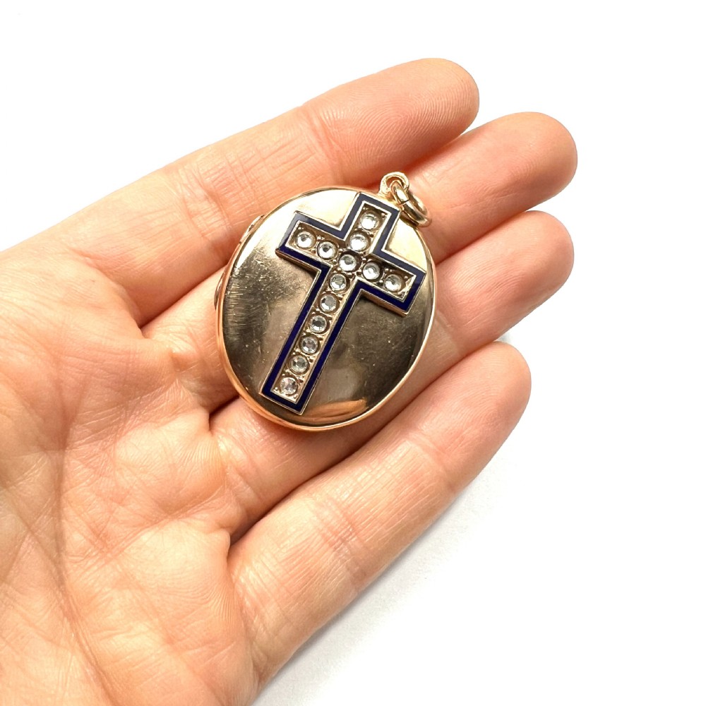 An oval rolled gold Victorian locket featuring a central blue enamelled cross set with round paste stones. View VIII