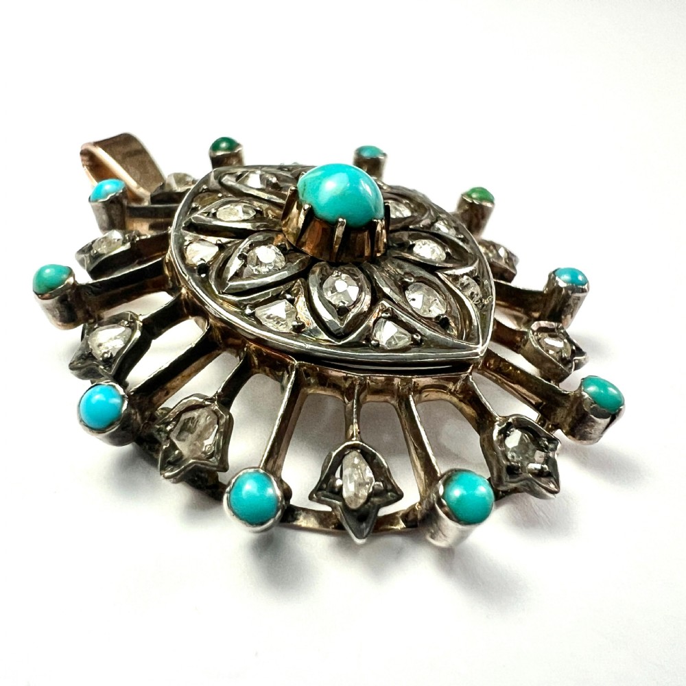 An antique circular pendant featuring a central turquoise cabochon framed by rose-cut diamonds and radiating turquoise-tipped spokes set in silver and gold. View II