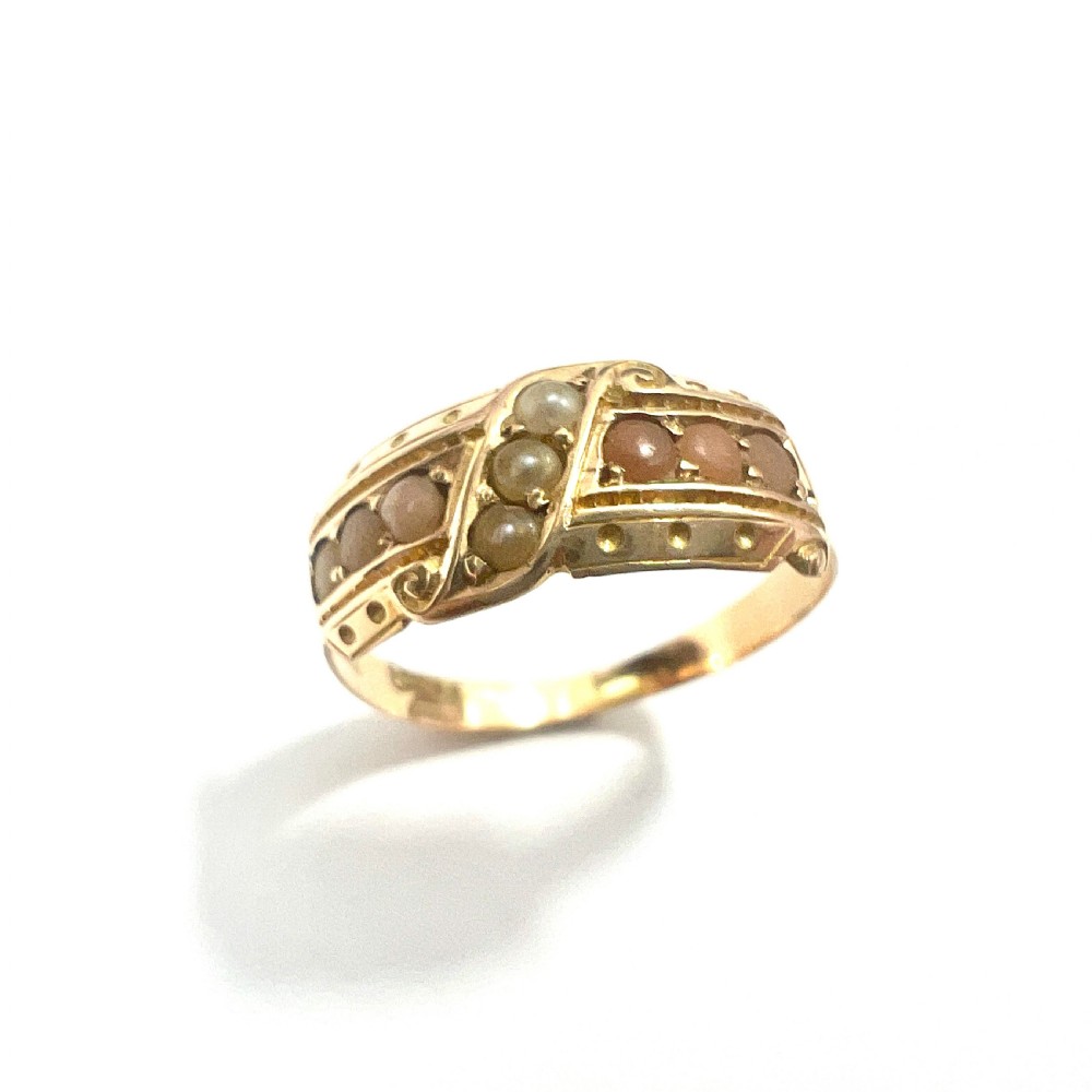 A Victorian 15 carat gold band ring set with rows of rounded seed pearls and pink coral cabochons featuring carved side scrollwork. View II