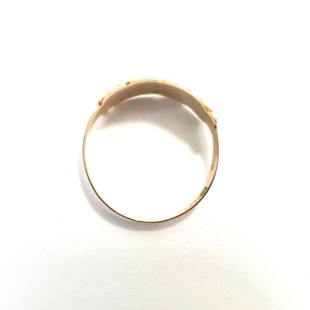 A Victorian 15 carat gold band ring set with rows of rounded seed pearls and pink coral cabochons featuring carved side scrollwork. View V