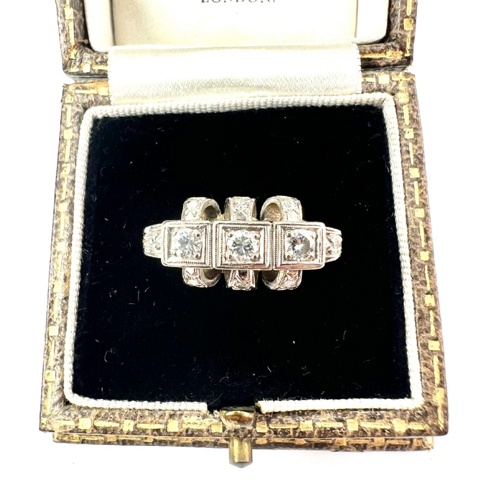 A vintage diamond engagement ring featuring three square-set diamonds in platinum and 14ct gold with geometric openwork detailing.