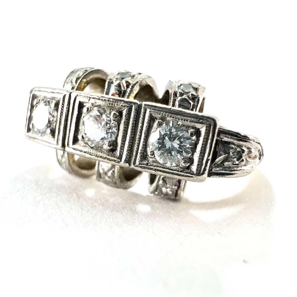 A vintage diamond engagement ring featuring three square-set diamonds in platinum and 14ct gold with geometric openwork detailing. View III