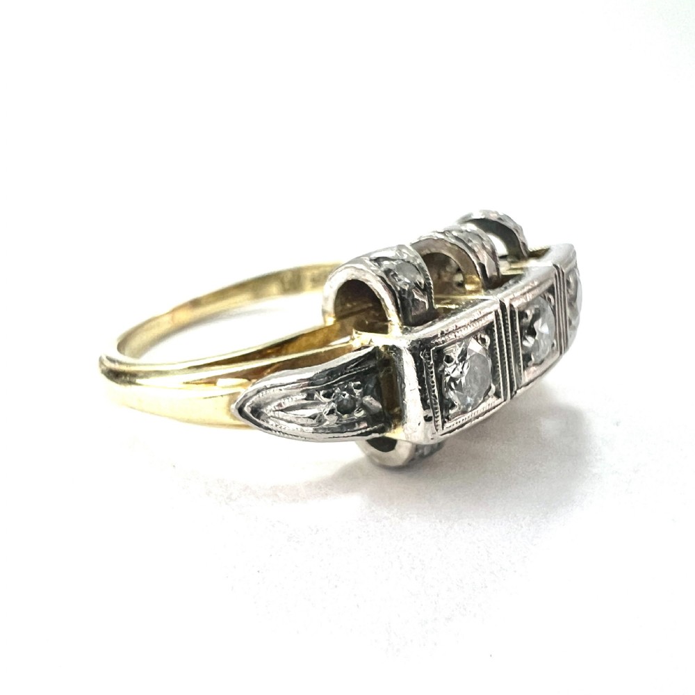 A vintage diamond engagement ring featuring three square-set diamonds in platinum and 14ct gold with geometric openwork detailing. View V