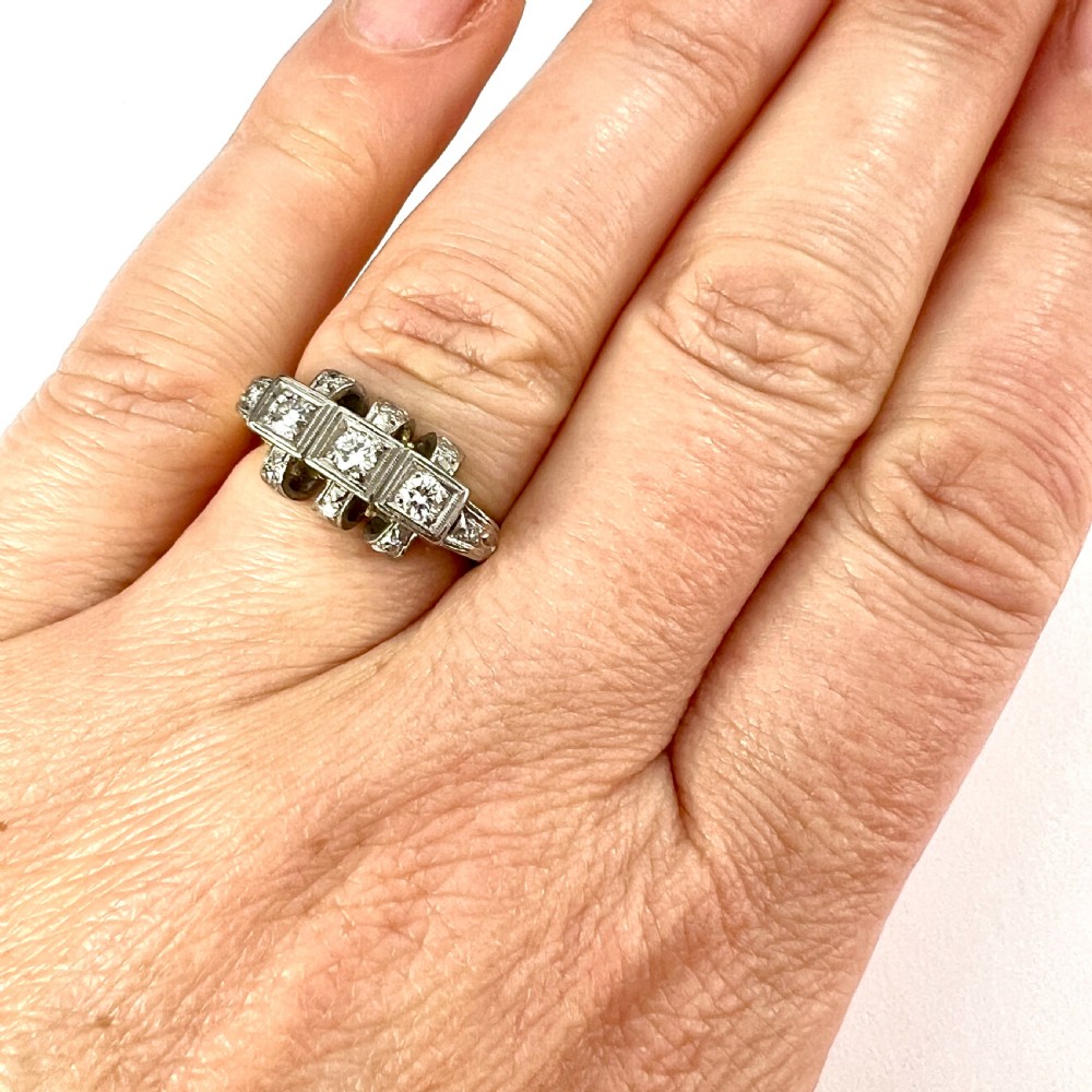 A vintage diamond engagement ring featuring three square-set diamonds in platinum and 14ct gold with geometric openwork detailing. View IX