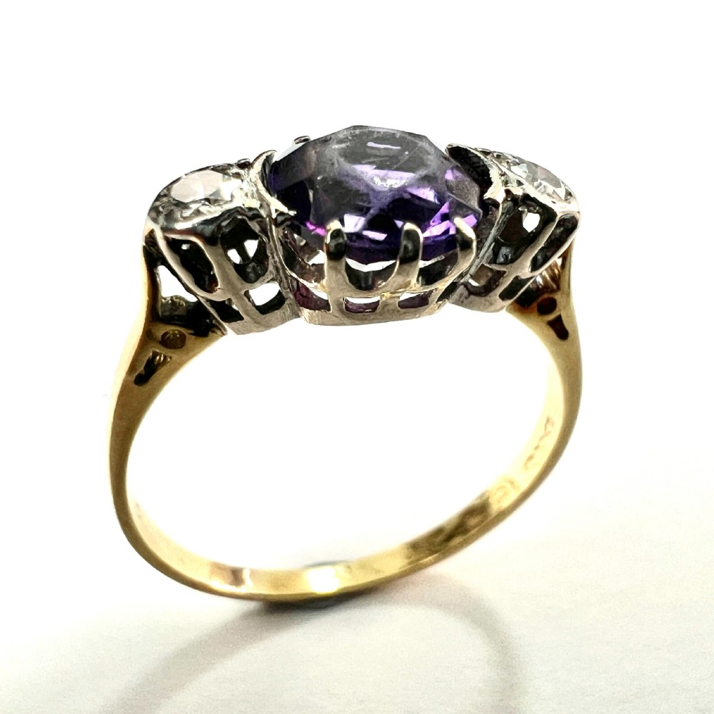 An antique 18ct yellow gold ring featuring a round purple central amethyst flanked by two diamonds in platinum settings. View II