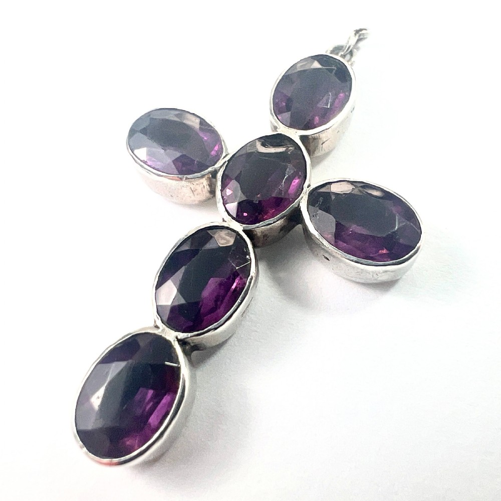 A Georgian silver cross pendant set with six oval faceted purple paste stones in closed collet mounts.