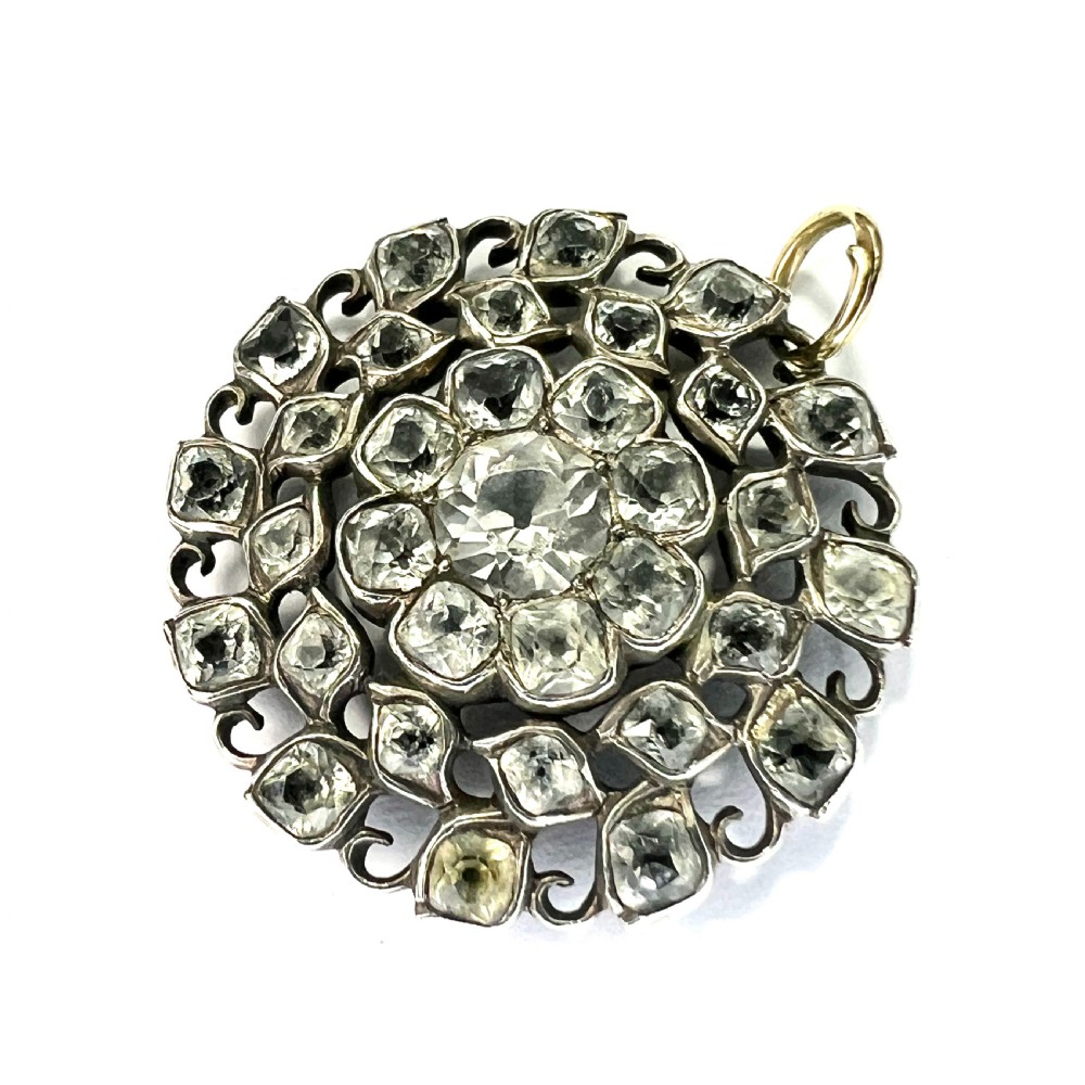 A circular Georgian silver pendant featuring faceted clear paste glass stones with black dot culets arranged in a floral cluster pattern. View II
