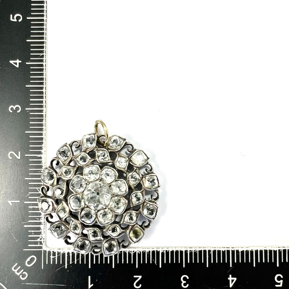 A circular Georgian silver pendant featuring faceted clear paste glass stones with black dot culets arranged in a floral cluster pattern. View IV