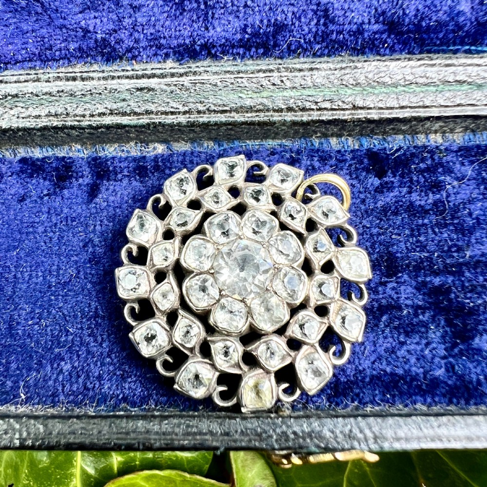 A circular Georgian silver pendant featuring faceted clear paste glass stones with black dot culets arranged in a floral cluster pattern. View V