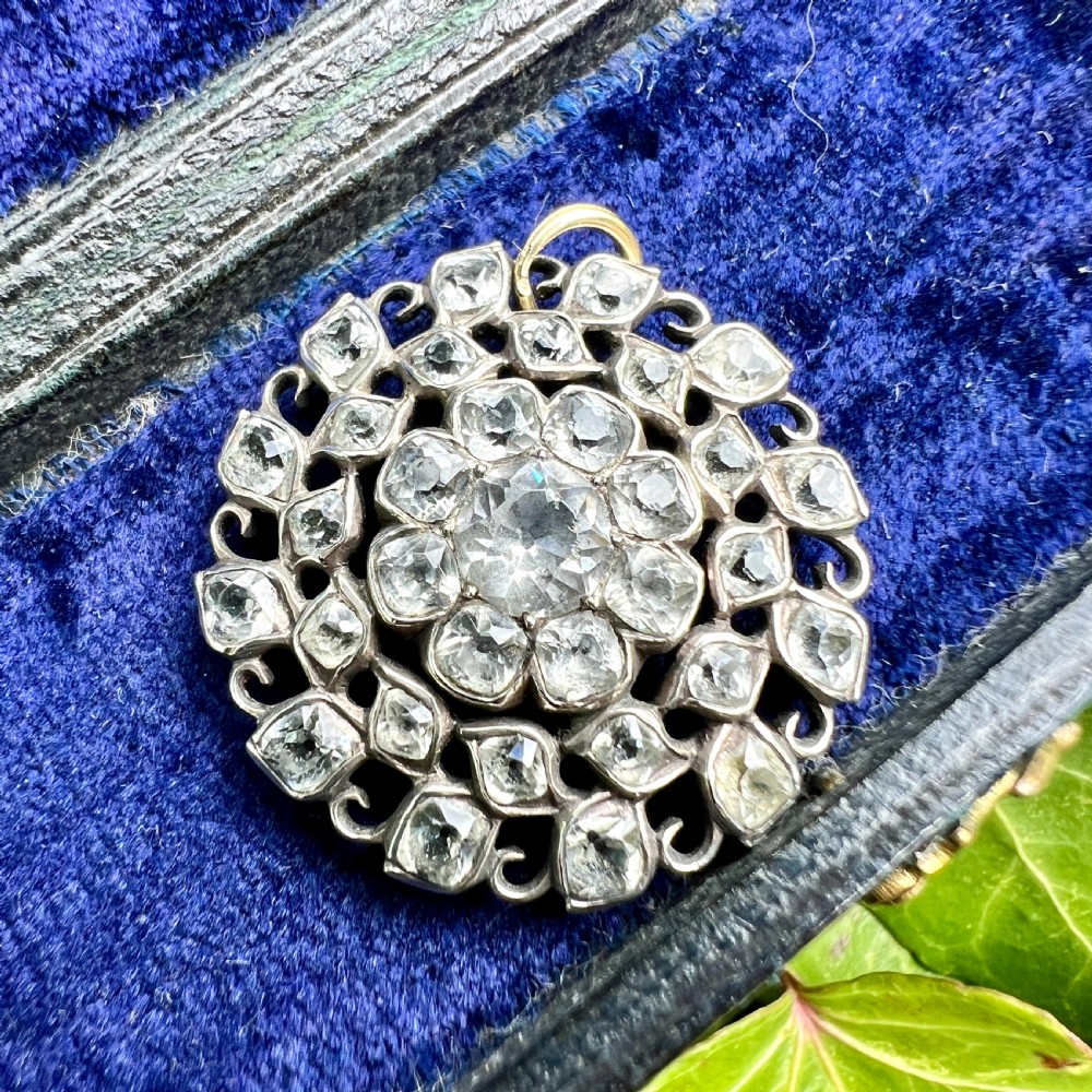 A circular Georgian silver pendant featuring faceted clear paste glass stones with black dot culets arranged in a floral cluster pattern. View VII