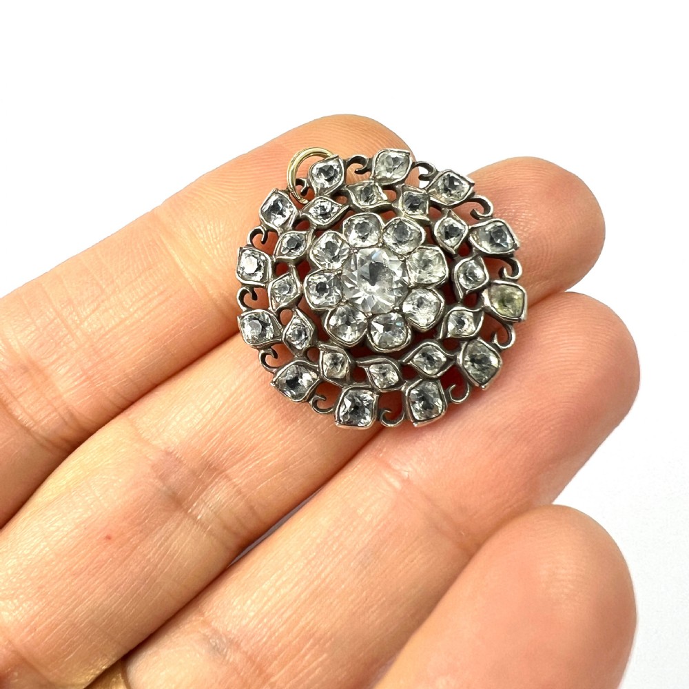 A circular Georgian silver pendant featuring faceted clear paste glass stones with black dot culets arranged in a floral cluster pattern. View VIII