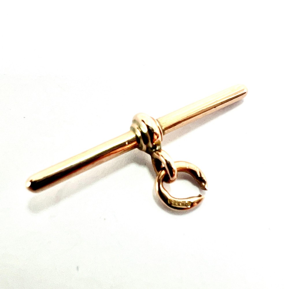 A polished 9ct rose gold Victorian albert T-bar pendant features a central crossbar and an attached jump ring.