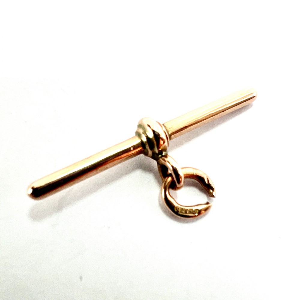 A polished 9ct rose gold Victorian albert T-bar pendant features a central crossbar and an attached jump ring. View III