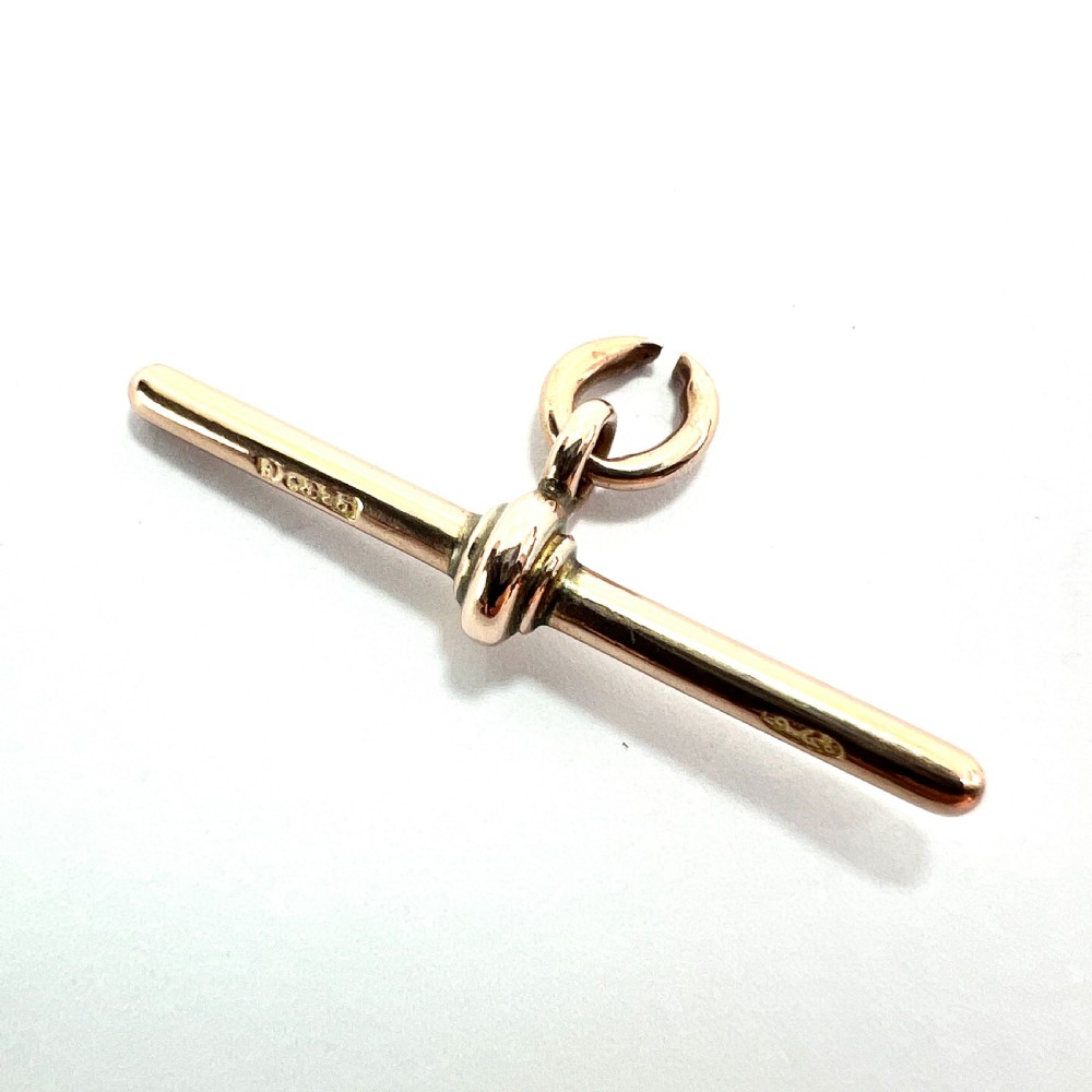 A polished 9ct rose gold Victorian albert T-bar pendant features a central crossbar and an attached jump ring. View V
