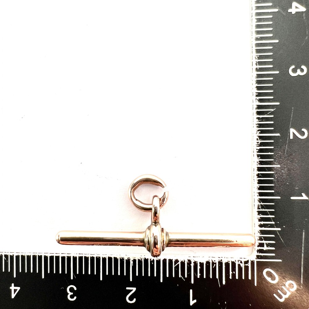 A polished 9ct rose gold Victorian albert T-bar pendant features a central crossbar and an attached jump ring. View VI
