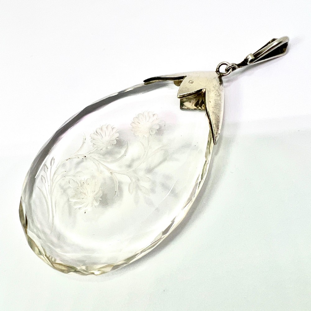 A clear glass teardrop pendant reverse-engraved with a floral motif, topped with a silver decorative cap set with faceted marcasite stones. View III